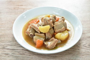 boiled pork bone with potato and carrot stew on plate
