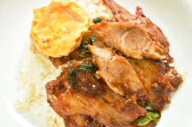spicy stir fried barbecue pork neck with chili and basil leaf curry topping egg and rice on plate  