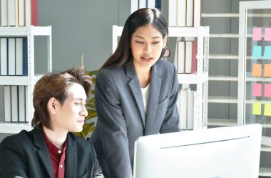 Asian business man and woman looking at computer laptop screen to discuss and working in office 