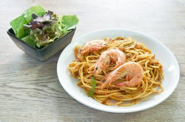 Baharatlı kızarmış spagetti karidesi, acı biberli ve fesleğen yaprağıyla tabakta Tom yum sosu, birkaç taze sebze salatası.