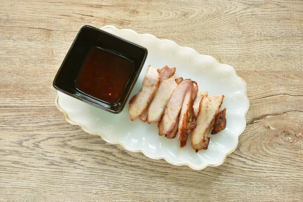 grilled pork neck slice on plate dipping spicy sauce