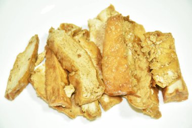 Kızarmış soya peyniri tabakta baharatlı sos beyaz arka planda.