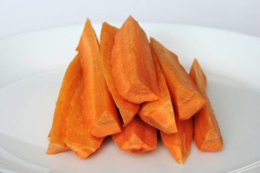 Beyaz bir tabağa turuncu havuç yapışıyor.