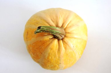 Sarı olgun bir balkabağının yakın plan resmi, beyaz arka plan.