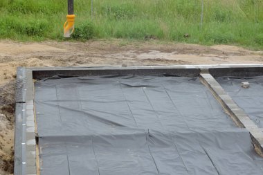 Beton bir kamyonun borusu beton kaplama dökmeye hazır, rutubetli zarı bir temele ve yalıtılmış temel duvarlarına yerleştirilmiş.
