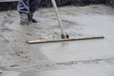  Islak betonu yüzdüren bir bina işçisi