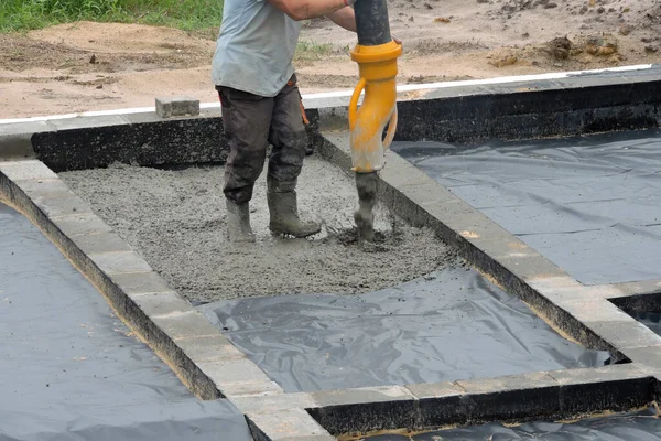 A building worker pouring a concrete slab foundation using a hose of a concrete pump truck