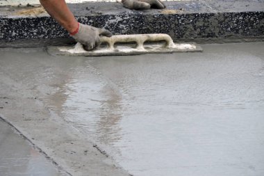 Islak betonu yüzdüren bir inşaat işçisi