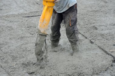 Beton bir kamyonun hortumunu kullanarak beton bir temel döken bir inşaat işçisi.