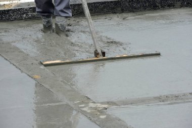  Islak betonu yüzdüren bir bina işçisi