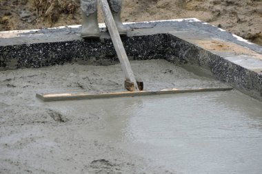  Islak betonu yüzdüren bir bina işçisi