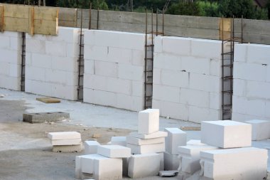 A steel reinforcement for pillars on the first floor of a house under construction, a wooden formwork for a reinforced concrete beam, walls made of cellular concrete, some aac blocks