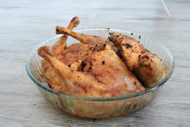 Dört baharatlı kızarmış tavuk bacağı. Cama dayanıklı bir kap, gri ahşap arka plan.