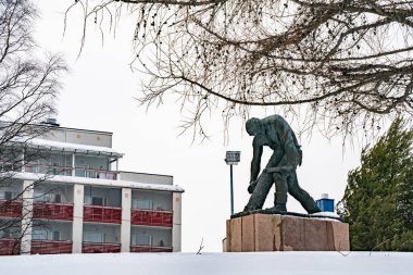 Rovaniemi, Finlandiya - 18 Mart 2022: Finlandiya 'nın Rovaniemi şehrinde kar yağışlı bir günde ağaç kesen bir oduncunun bronz heykeli.