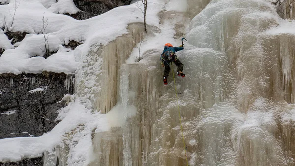 Finlandiya 'da donmuş bir şelalenin buz duvarına tırmanan bir uçurum tırmanıcısı.
