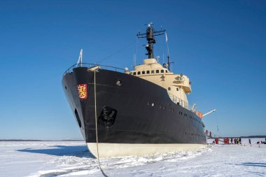 Rovaniemi, Finlandiya - 21 Mart 2022: Donmuş baltık denizinde demirlemiş bir buzkıran gemisi olan Sampo, güneşli bir kış gününde, yanında yüzme kıyafetleri giymiş turistler.