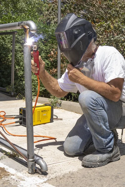 Jerusalem, Israel - May 18th, 2022: A man welding a metal railing outdoors on a sunny day.