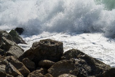 Kayaların üzerinde köpük ve su damlaları oluşturan bir deniz dalgası..