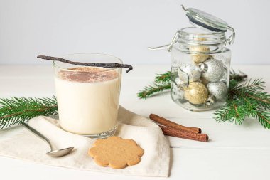Bir bardak yumurtalı kokteyl ve gri arka planda Noel süslemeleri.