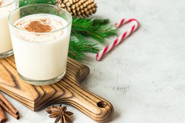 İki bardak yumurtalı kokteyl ve gri arka planda Noel süslemeleri.