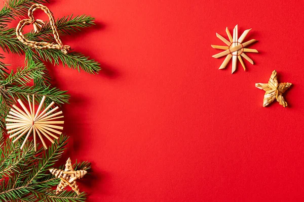 Decorações de Natal de palha e ramos de abeto no fundo vermelho — Fotografia de Stock