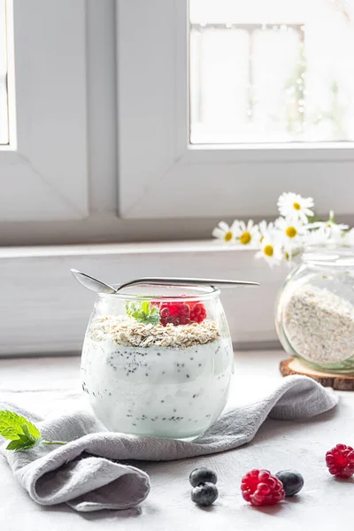 Un vaso con yogur en capas, semillas de chía, avena y bayas, servido para el desayuno —  Fotos de Stock