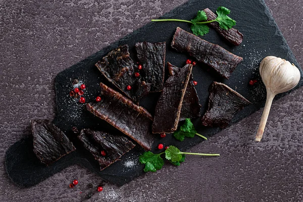 Slices of jerky meat on a dark backdround — стоковое фото