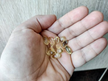 Bir insan avuç içinde çeşitli D3 vitamini kapsülleri bulundurur.