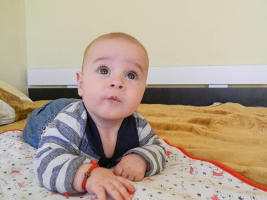 Bir erkek bebek yatakta yatıyor.