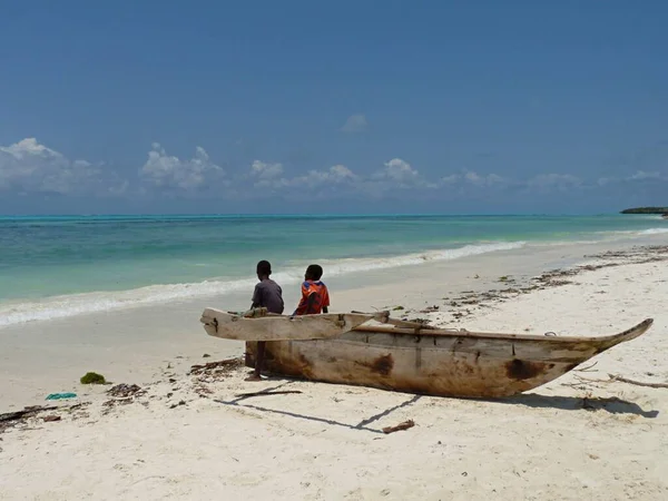 Zwei Jungen ruhen auf einem traditionellen Holzboot am jambischen Strand von Sansibar — Stockfoto