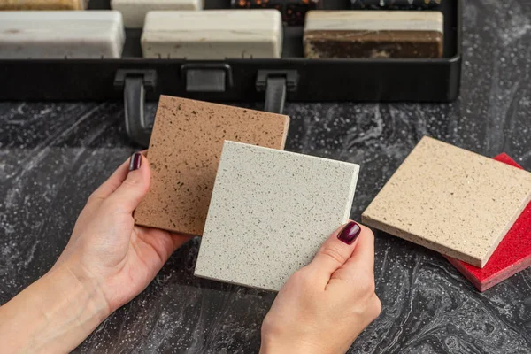 Choice of tiles. Female hands hold samples of tiles of different colors. Woman in store chooses bathroom tiles