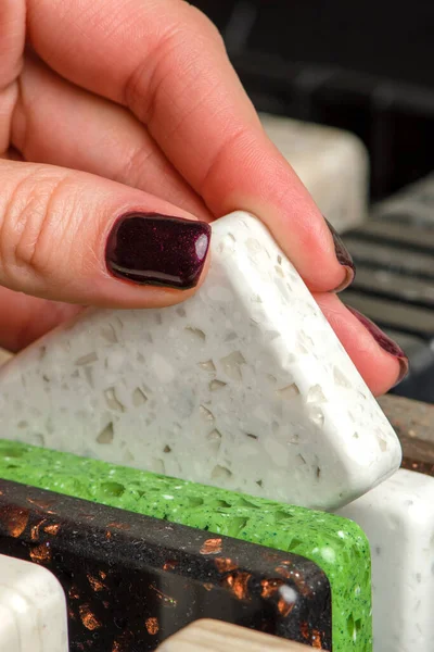 A woman chooses stone samples for a kitchen countertop. A set of multi-colored samples of artificial acrylic stone. — Stock Photo, Image