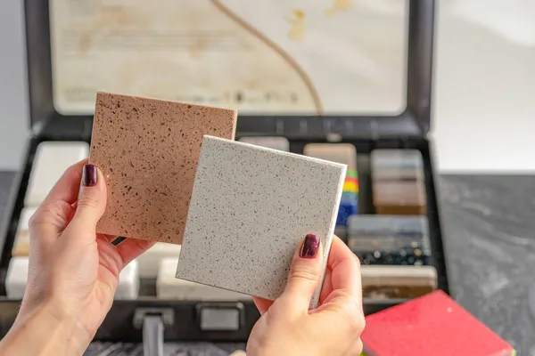 Samples of material for the countertop. Female hands are choosing interior elements for renovation. Samples of acrylic stone in hands. — Stock Photo, Image