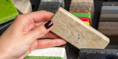 Bir kadın mutfak tezgahı için taş örnekleri seçiyor. Çok renkli yapay akrilik taş örnekleri..