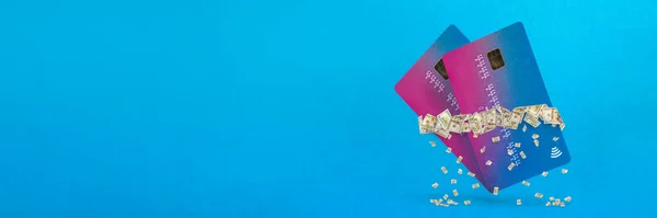 Παθητικό εισόδημα. Έννοια ταμειακών ροών. Παθητικά κέρδη. Μια πιστωτική κάρτα κρέμεται στον αέρα σε ένα μπλε φόντο που περιβάλλεται από δολάρια από τα οποία πέφτουν μικρά χαρτονομίσματα — Φωτογραφία Αρχείου