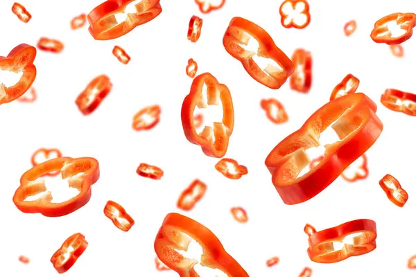Červená paprika nakrájená na plátky izolované na bílém pozadí. Padající plátky pepře v různých velikostech a s různými směry. — Stock fotografie