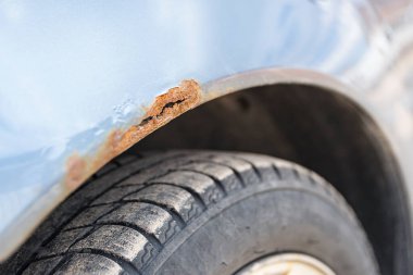 Bir araba gövdesinde metal aşınması, yakın plan. Arabanın kapısında pas var. Seçici odak