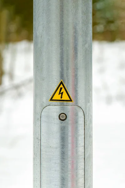 Lighting pole in the city. Electricity service door. Pasted yellow warning sign with lightning. High voltage — ストック写真