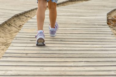 Dağlardaki ahşap patika. Tahta döşeme. Dağlardaki tahtalardan yapılmış dolambaçlı turist yolu. Kızların bacakları turist yolu boyunca dağlara gider.