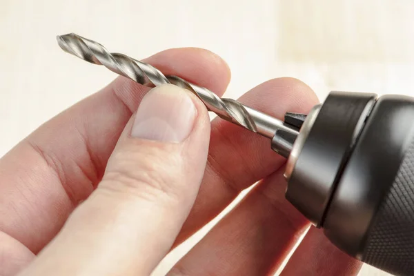 Installing a drill bit in a drill, hands take a drill and install it in a cordless drill chuck — Stock Photo, Image