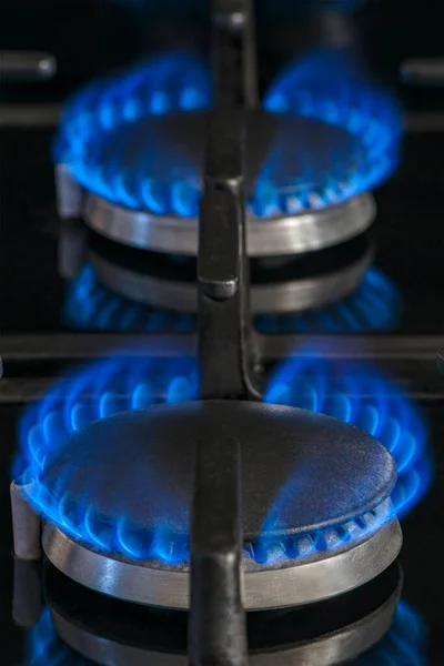 Combustion of natural gas, propane. Gas stove on a black background. Fragment of a gas kitchen stove with a blue flame, close-up. Energy crisis concept, rise in price or price of gas