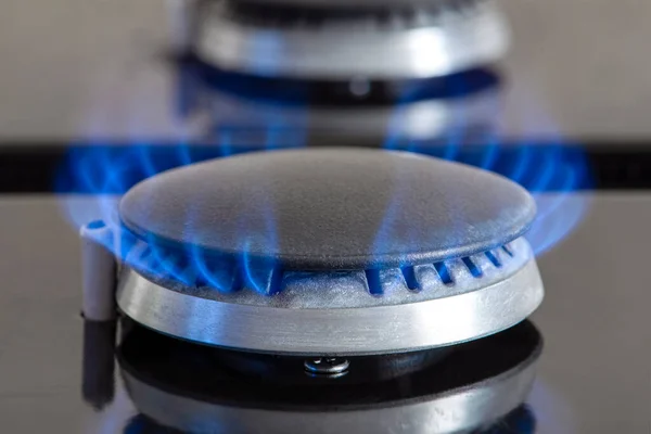 Combustion of natural gas, propane. Gas stove on a black background. Fragment of a gas kitchen stove with a blue flame, close-up. Energy crisis concept, rise in price or price of gas