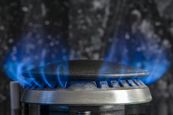 Combustion of natural gas, propane. Gas stove on a black background. Fragment of a gas kitchen stove with a blue flame, close-up. Energy crisis concept, rise in price or price of gas
