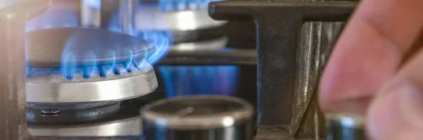 The cost of gas for domestic needs. The hand unscrews the gas burner in the kitchen. The use of gas as home heating in winter, during the cold season