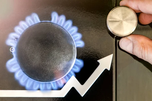 Gas price. Supply chains and the energy gas crisis. Gas stove with a burning flame and a graph arrow pointing up. Mans hand adjusts the gas supply.