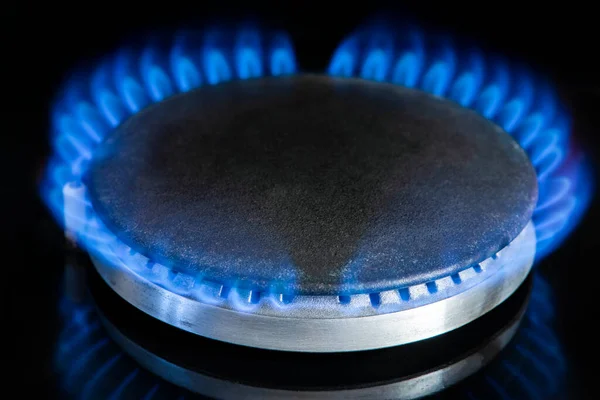 Gas stove on a black background. Fragment of a gas kitchen stove with a blue flame, close-up. Energy crisis concept, rise in price or price of gas