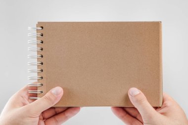 Elimde not defteri var. Beyaz arka plandaki bir adamın elindeki boş not defteri. Ellerin kitabı mesajsız tutsun. Elinde boş kapaklı bir kitap tutan bir adam var.