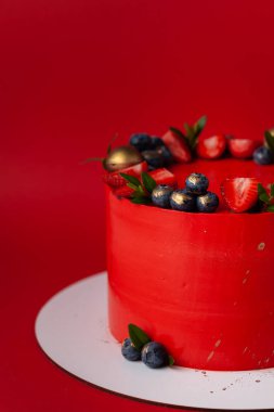 Büyük bir olay için krem peynirli kırmızı pasta. Altın süslemeli lüks pasta ve kırmızı arka planda böğürtlenler.