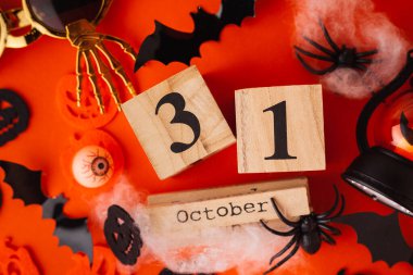 Korkunç yarasalar, turuncu arka planda örümcek ağı olan örümcekler. turuncu ve siyah balkabakları. Cadılar Bayramı arka planında 31 Ekim tarihli tahta bloklar takvimi