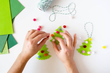 Beyaz masaüstünde Noel süsleri yapan bir kadın. Tepeden. Düz yatıyordu. Kumaştan yapılmış Noel ağacı